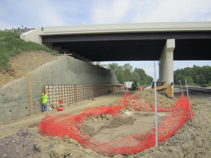 a highway bridge that is under construction with construction workers standing next to it