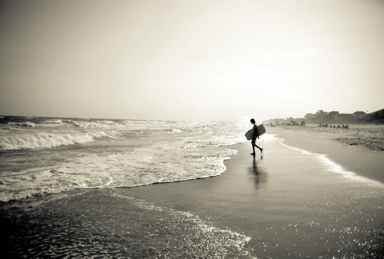 a surfer is carrying his surfboard into the water on the beach