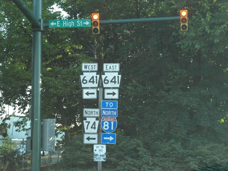 several road signs and red lights hanging on a traffic light