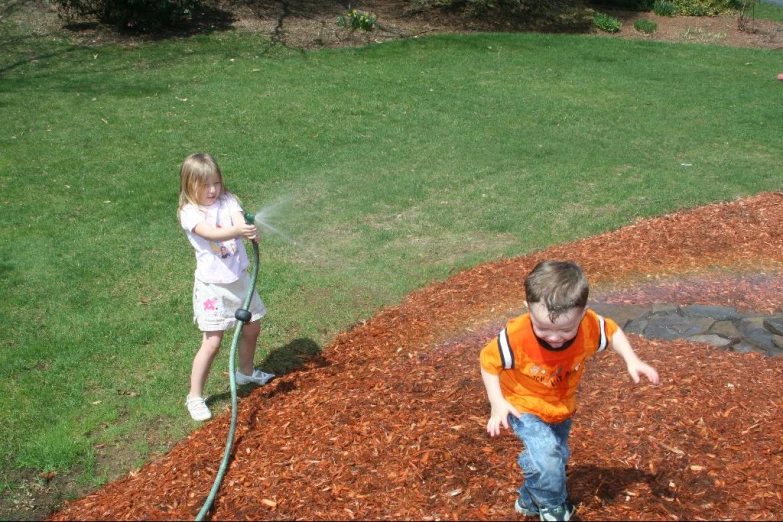 the two little boys are playing in the yard