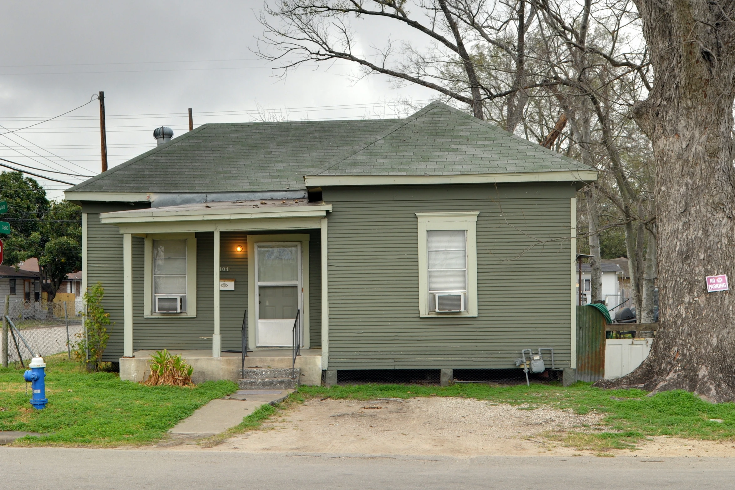 a green house with a tree and fire hydrant