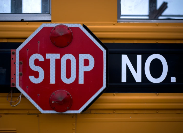 a stop sign that is mounted on the front of a school bus