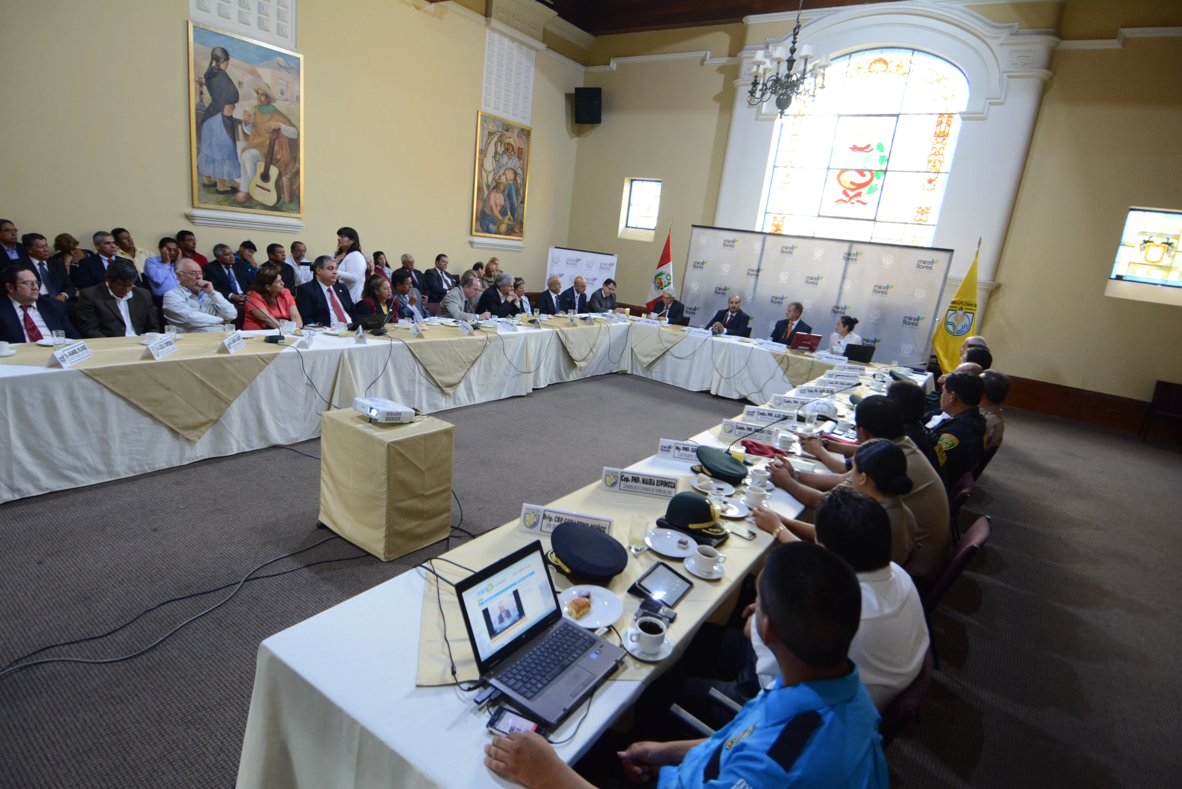 an audience sits at long tables with laptops in front of them