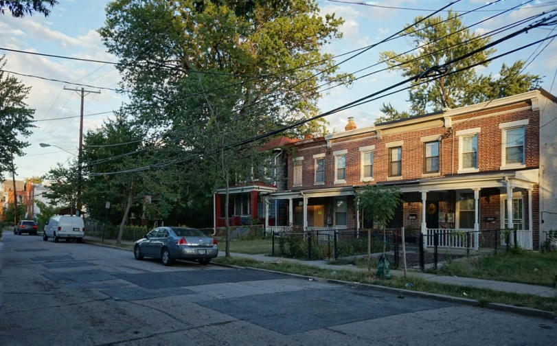 the cars are driving down the road in front of this row of brick houses