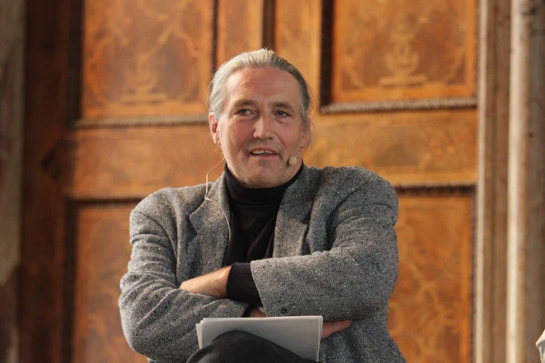 an older man with his arms folded sitting down