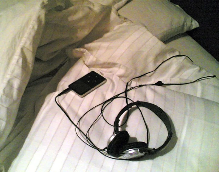 a close up of an unmade bed with two headphones