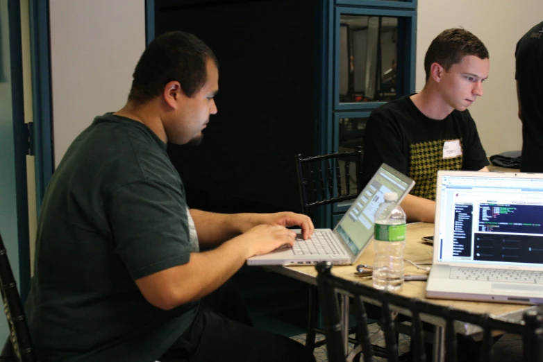 two men with laptops that have their lids open