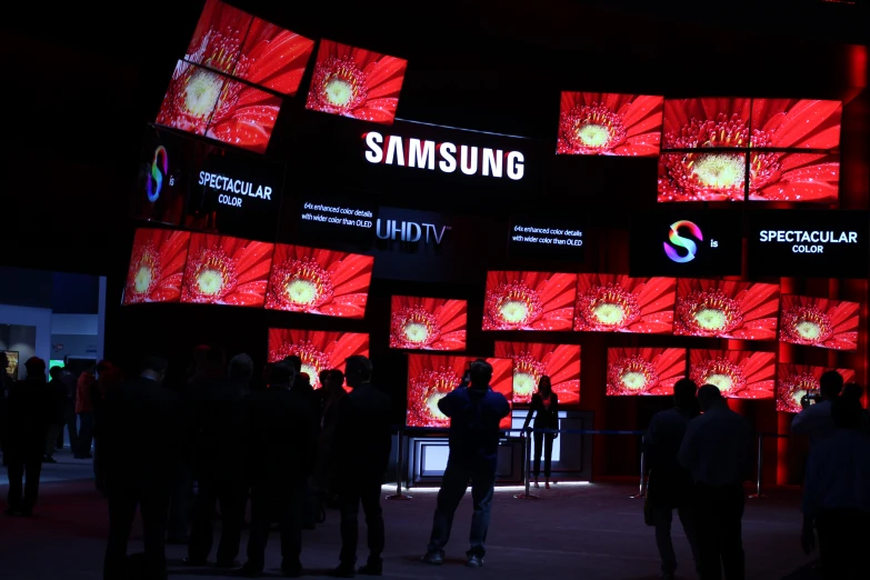 a group of people standing in front of three samsung logo