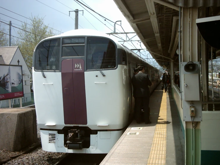 a white and maroon train at the station