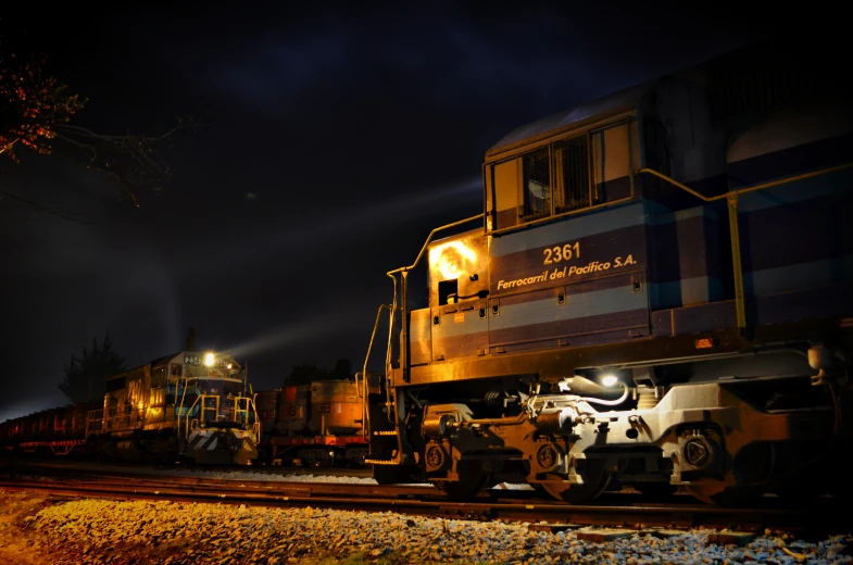 a train with lights on next to a railroad station