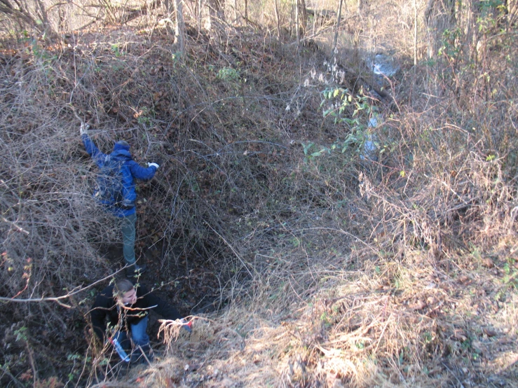 a man in a blue jacket standing on a rope that is partially buried in a field