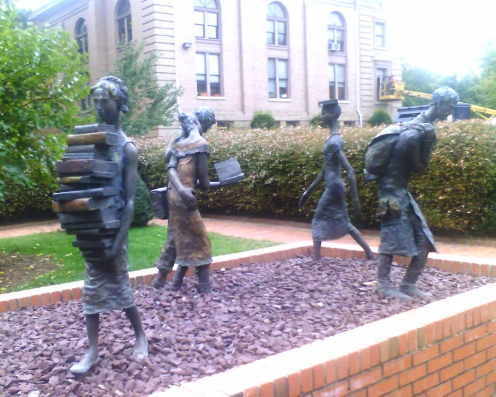 three statues of people holding books in the shape of people