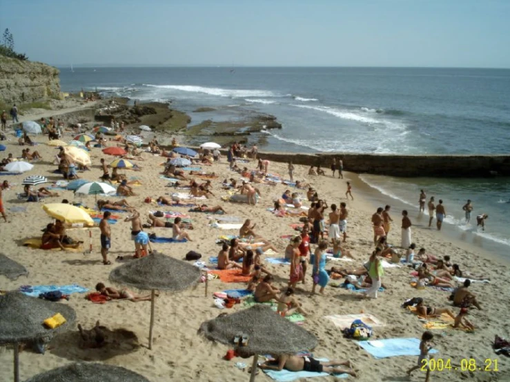 people at the beach, one in the foreground holding a yellow umbrella