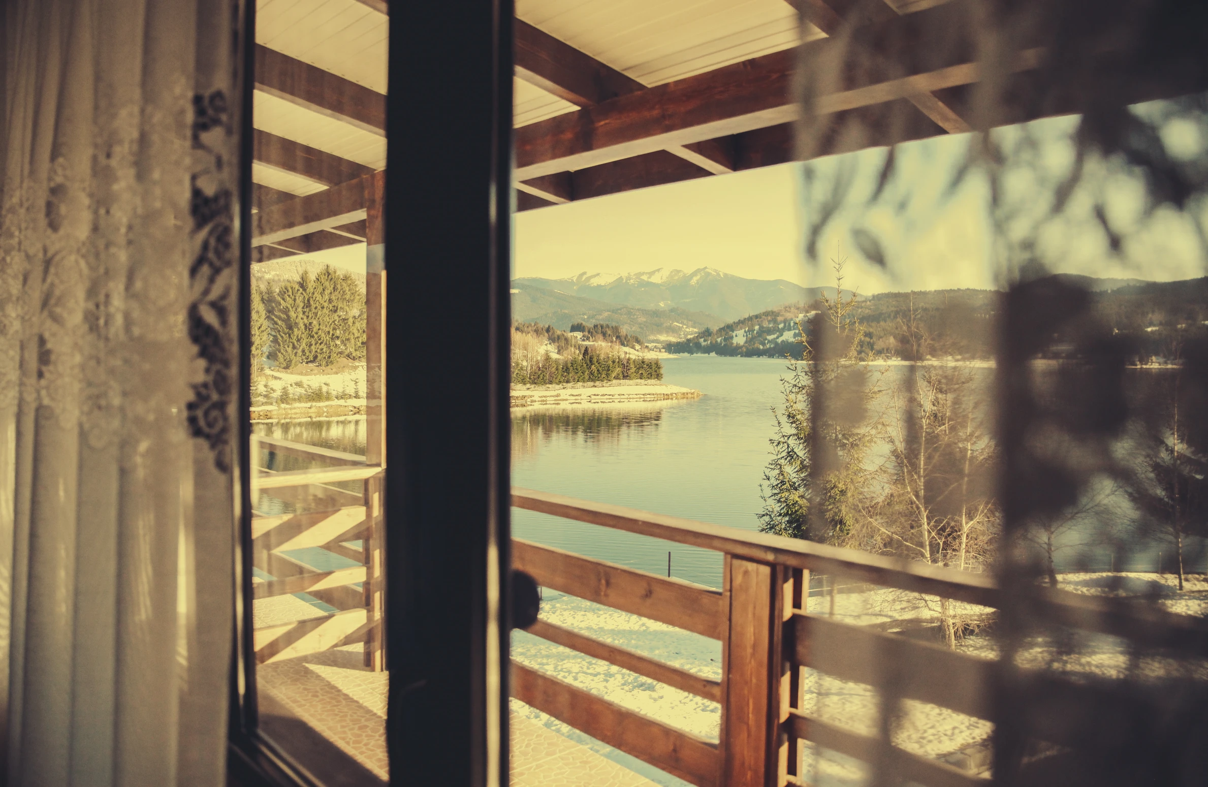 the view out a window at a lake with mountains in the distance
