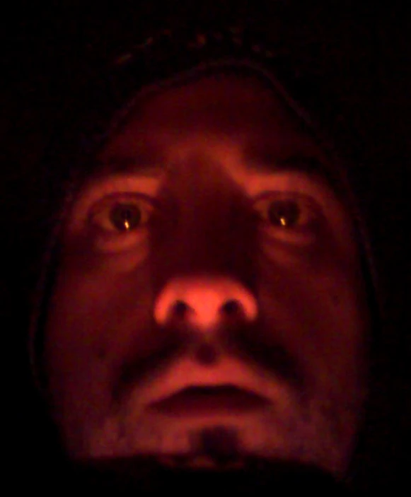a man is staring at the camera in the dark