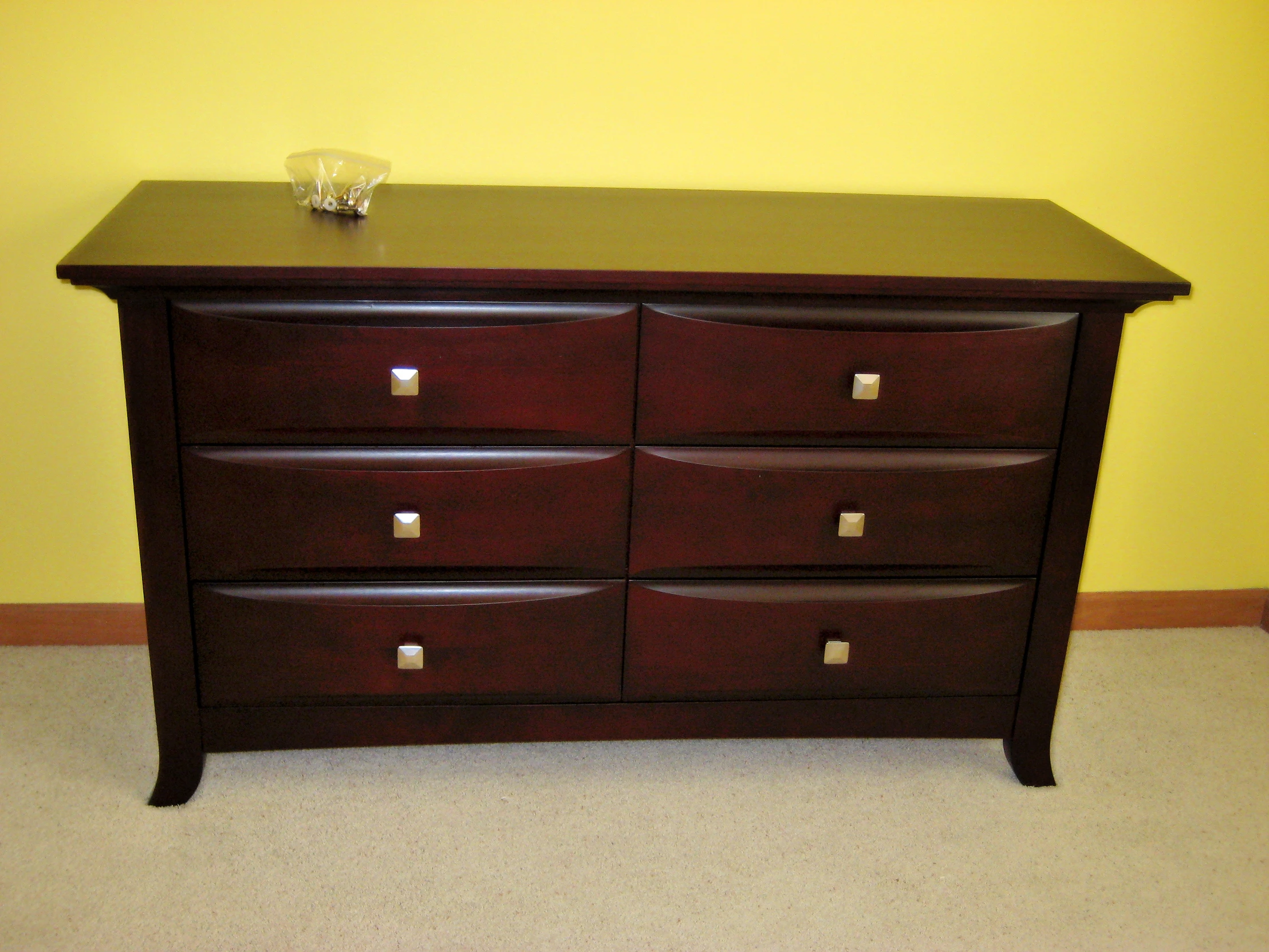 the wooden dresser has two small bowls on top