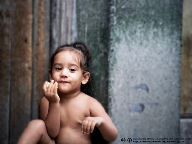 a  toddler sitting in front of a doorway and waving