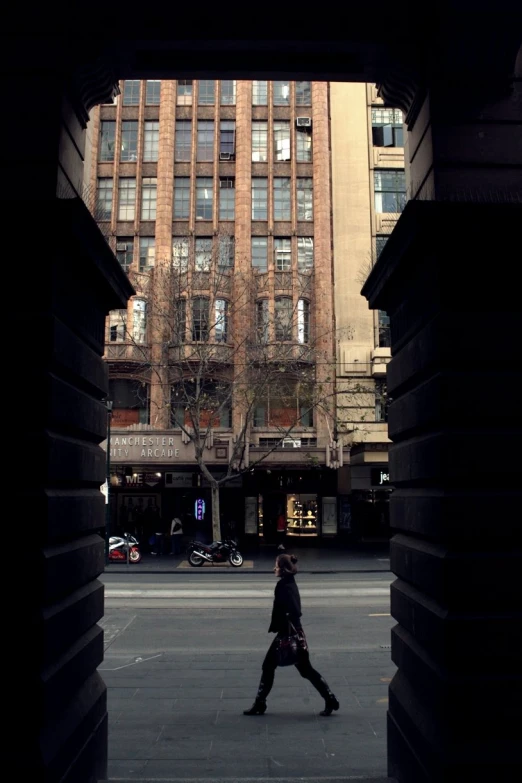 there is a man walking past a large building