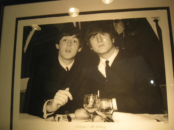 the two boys are posing for a pograph in front of a table with glasses and wineglasses