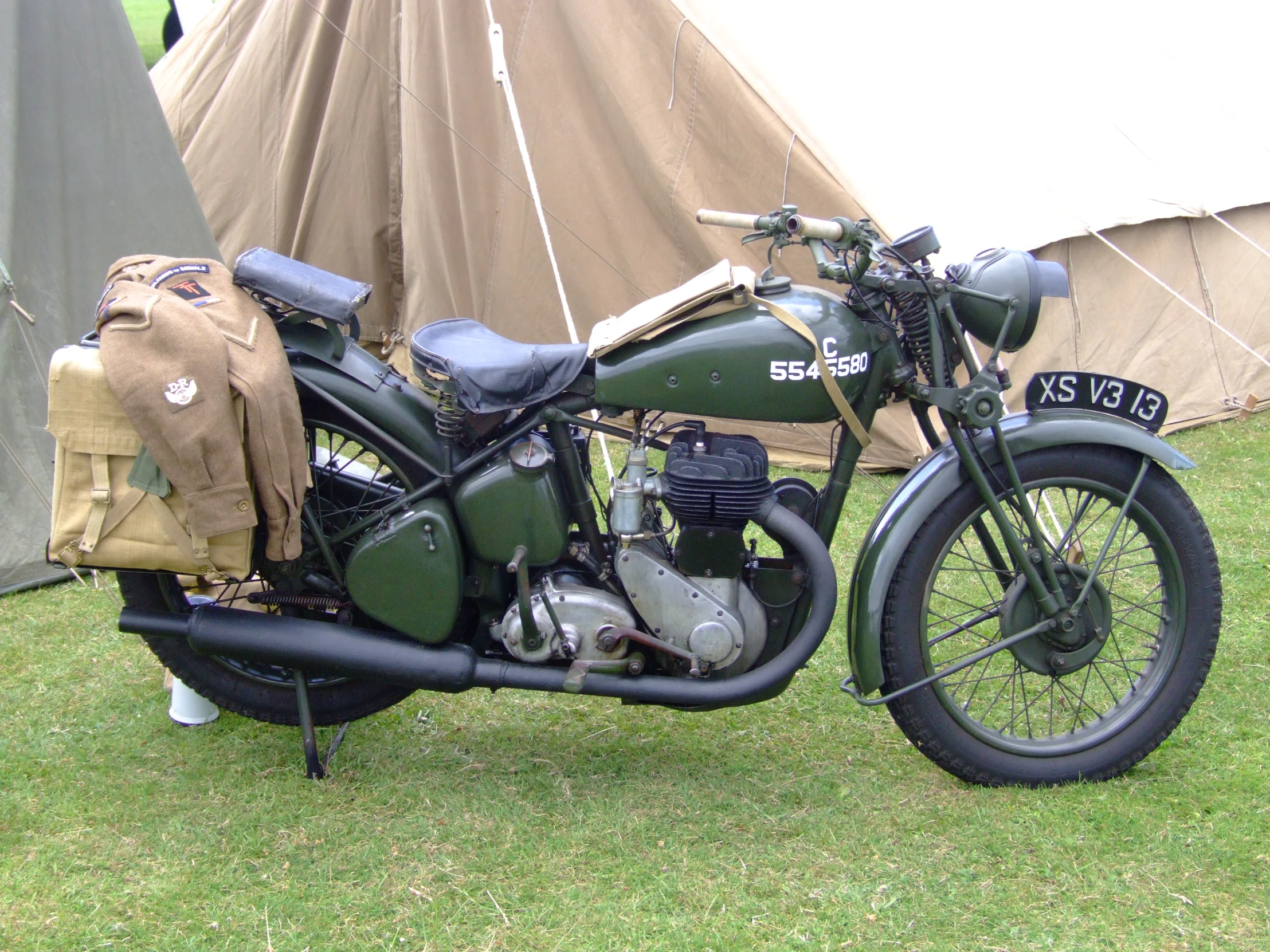 an old green motorcycle with side bags on the handlebar