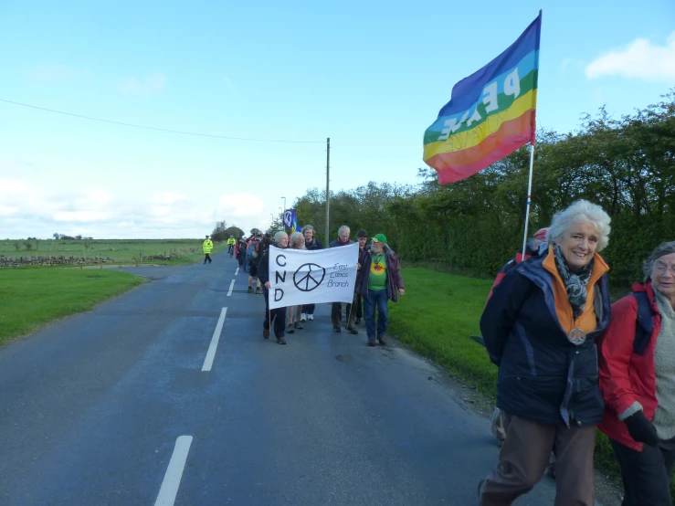 people standing along the street holding up a rainbow flag