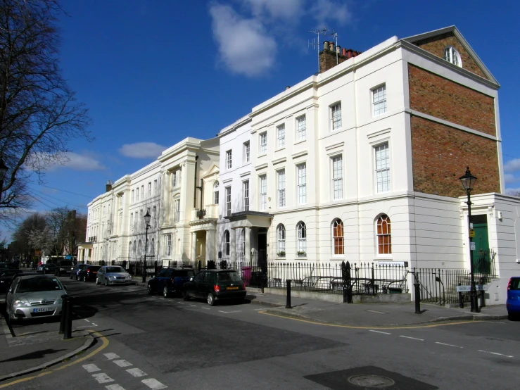 some cars are parked on the street in front of white buildings