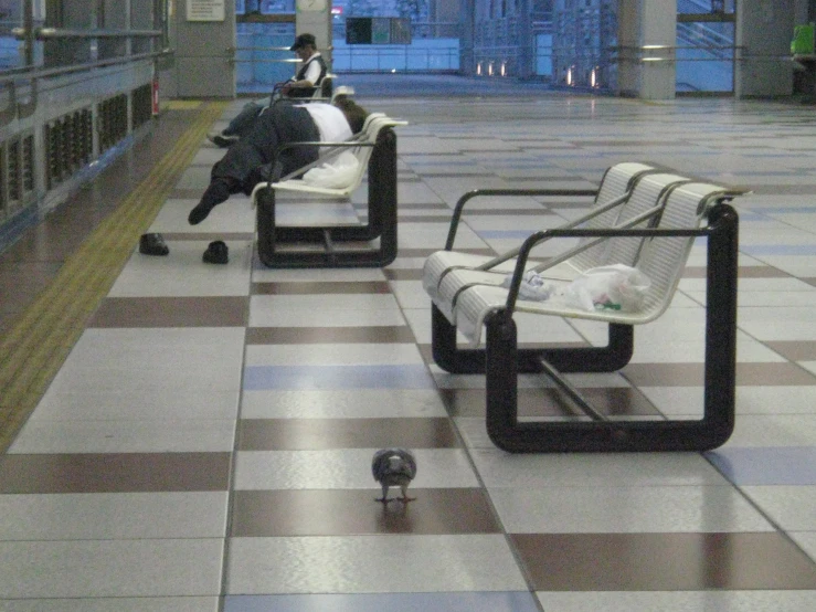 a man sitting on some chairs looking at another person sleeping