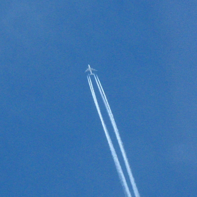 an airplane flying in the sky, trailing smoke behind it