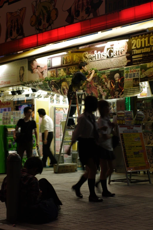 people are gathered outside of a store front at night