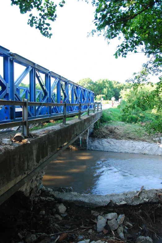 an old bridge crossing a narrow river on concrete