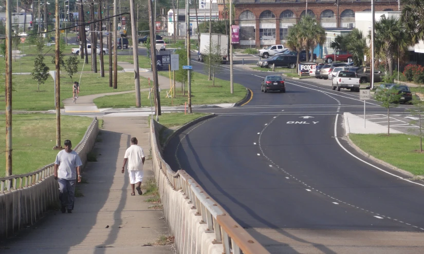 two people walking down a city road next to a tall pole