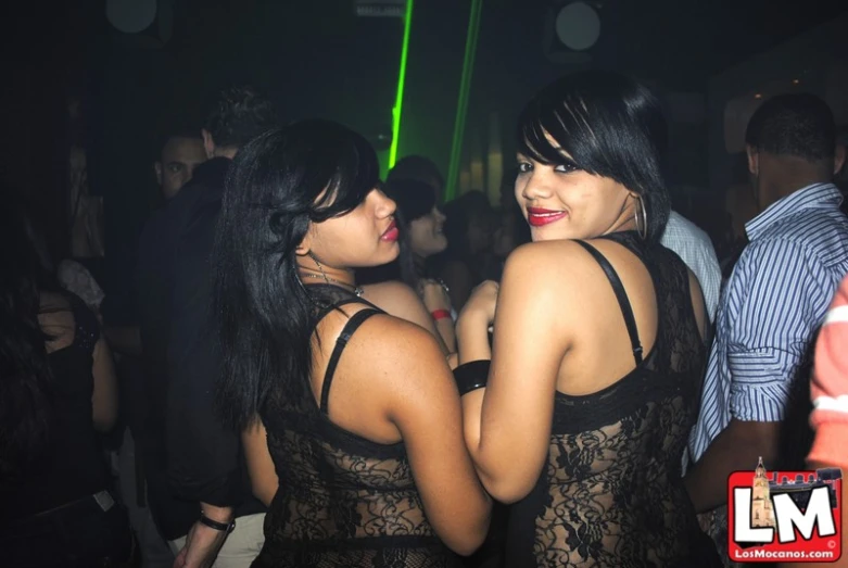 two women dressed up and standing in a club