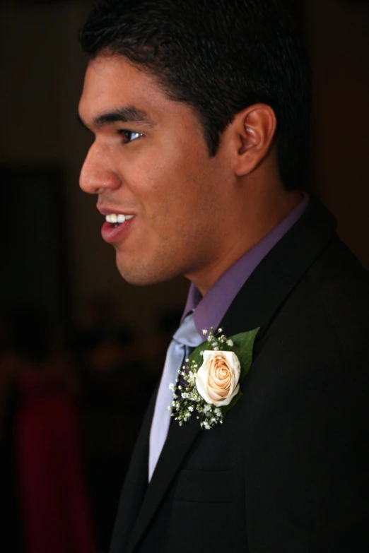 a man smiles wearing a boutonniere and flowers on his lapel