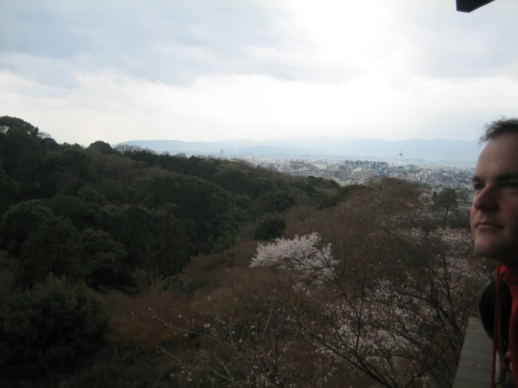 a man looking at the city and trees while he stands next to him