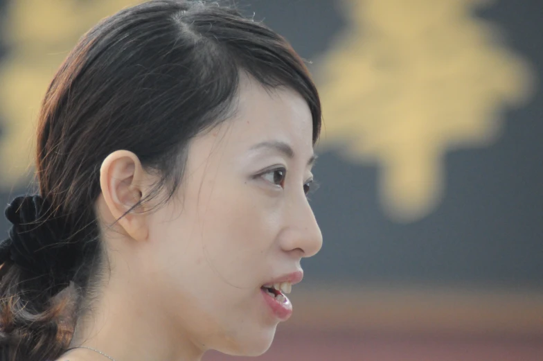 a woman is talking into a microphone with chinese writing on the back of her ear