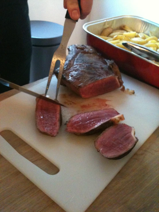 a knife cuts meat from a plate with other food