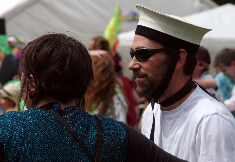 a woman walking alongside a man in a sailor hat