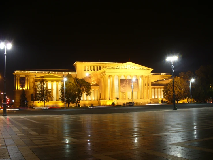 a building with lights on is next to the street