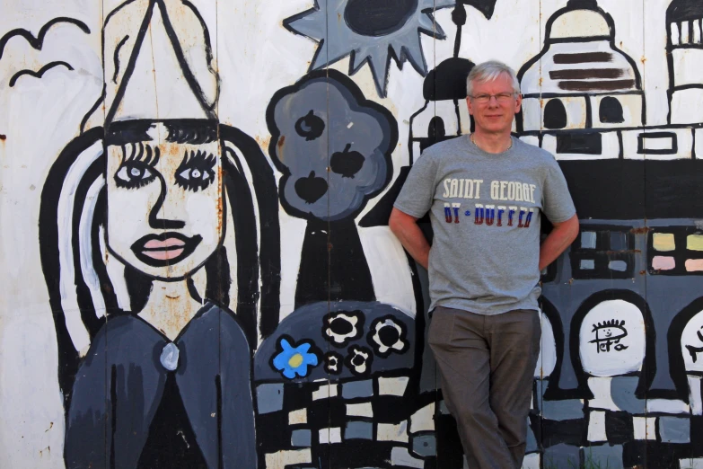 a man standing by a painting on the wall