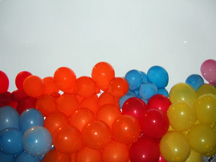 a bunch of balloons with colors and sizes that are blue, orange and red