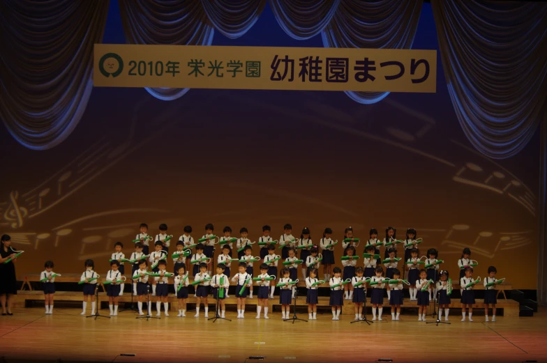 an image of choir on stage with a soundboard