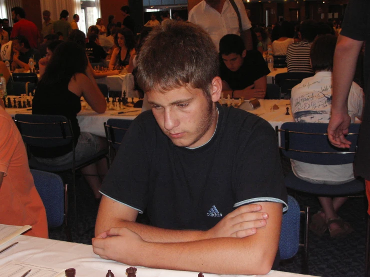 a young man sitting at a table looking at a phone