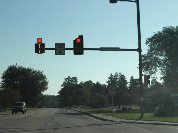 a traffic light on a street with a car going down the road