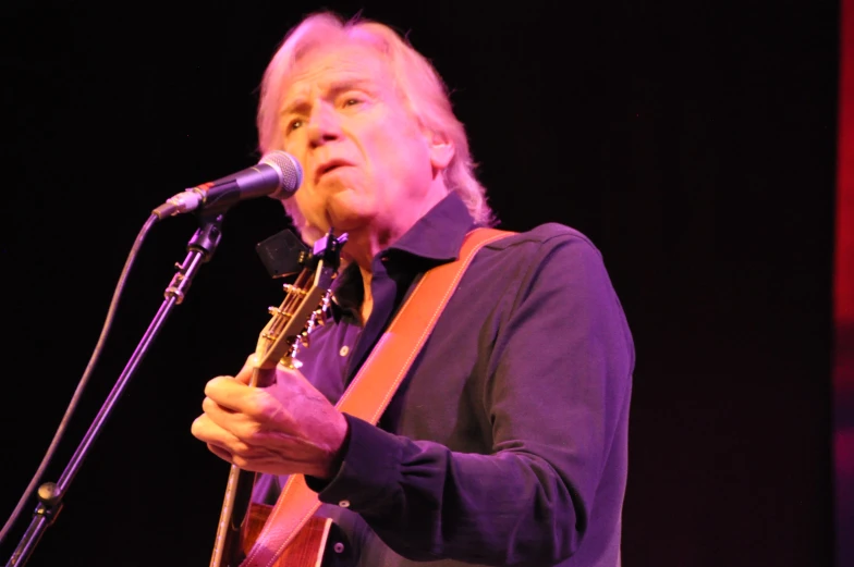 the musician is standing at the microphone and playing his guitar