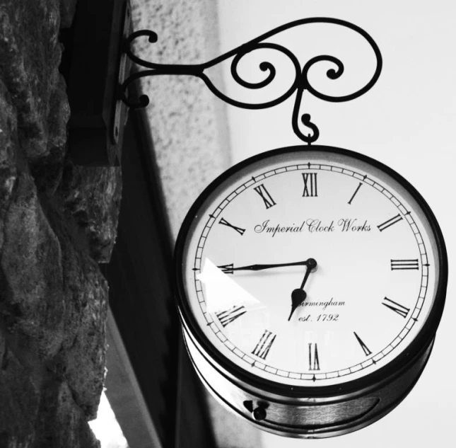 an outdoor clock sits on the side of the building