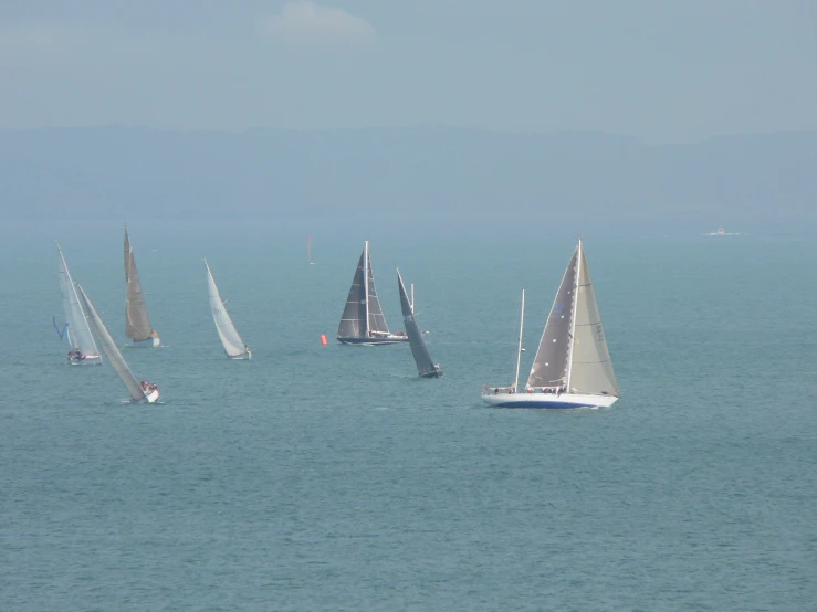 sailboats sailing in open water off the coast