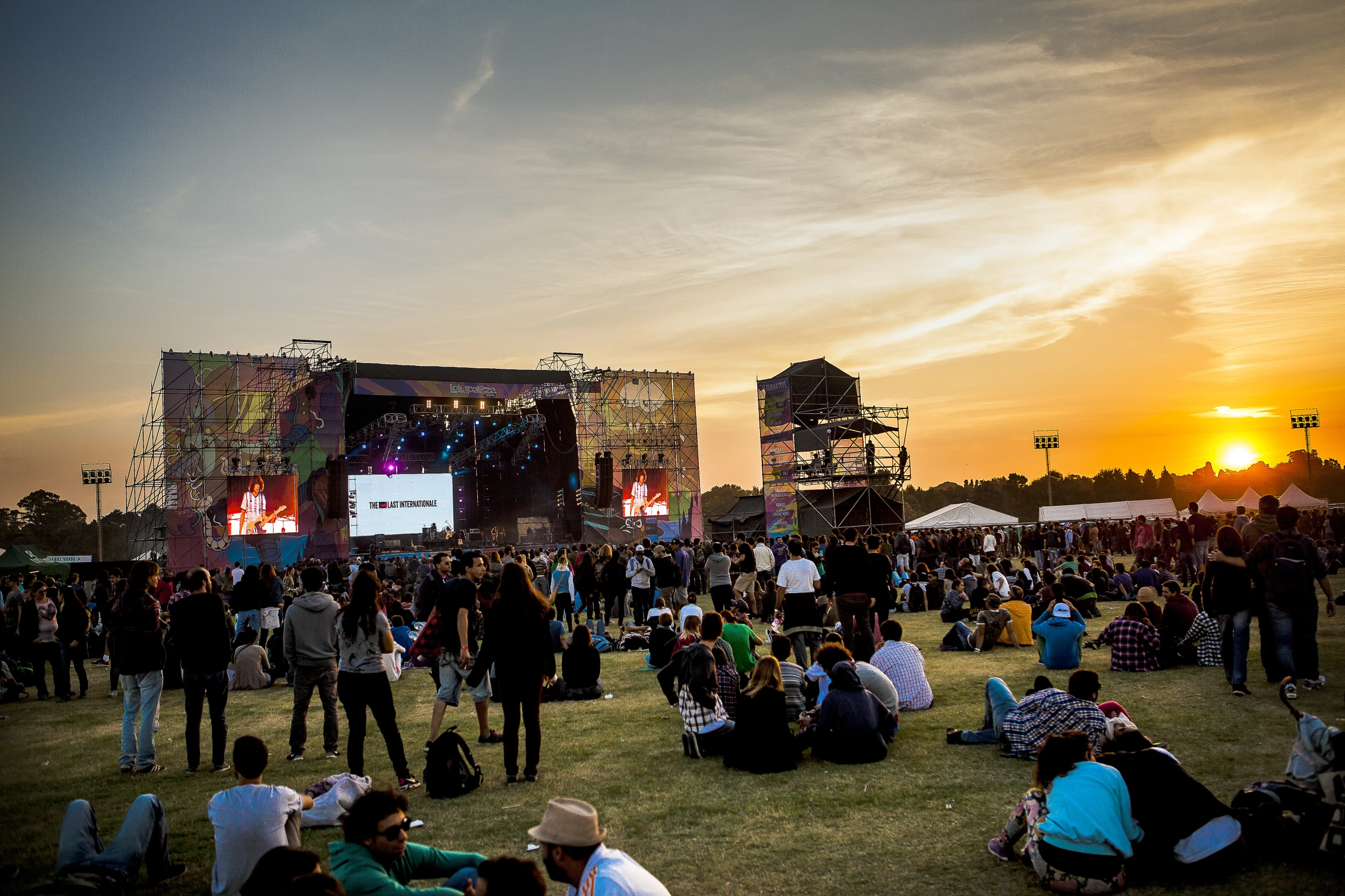 a group of people gathered at a festival watching a sunset