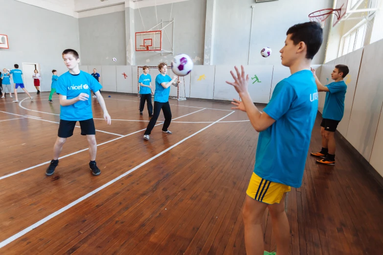 boys in blue jerseys are playing basketball on a hard wood court