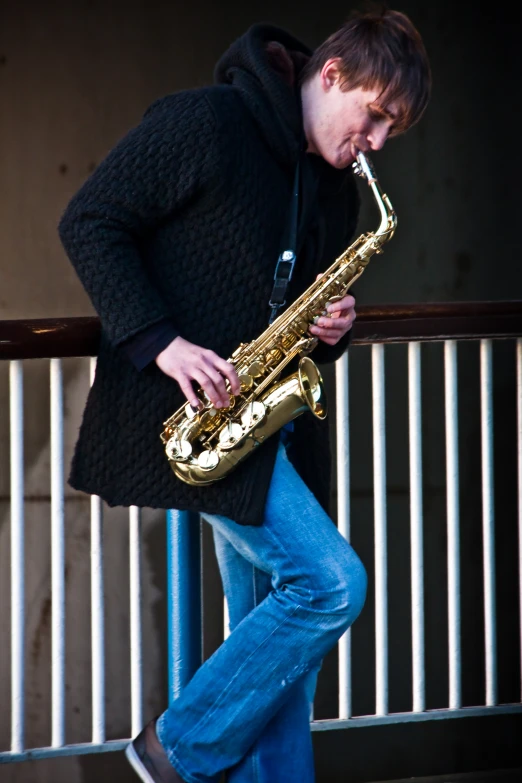 a person leaning on the railing playing a saxophone