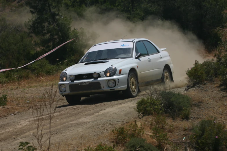 white car driving down dirt road during daytime